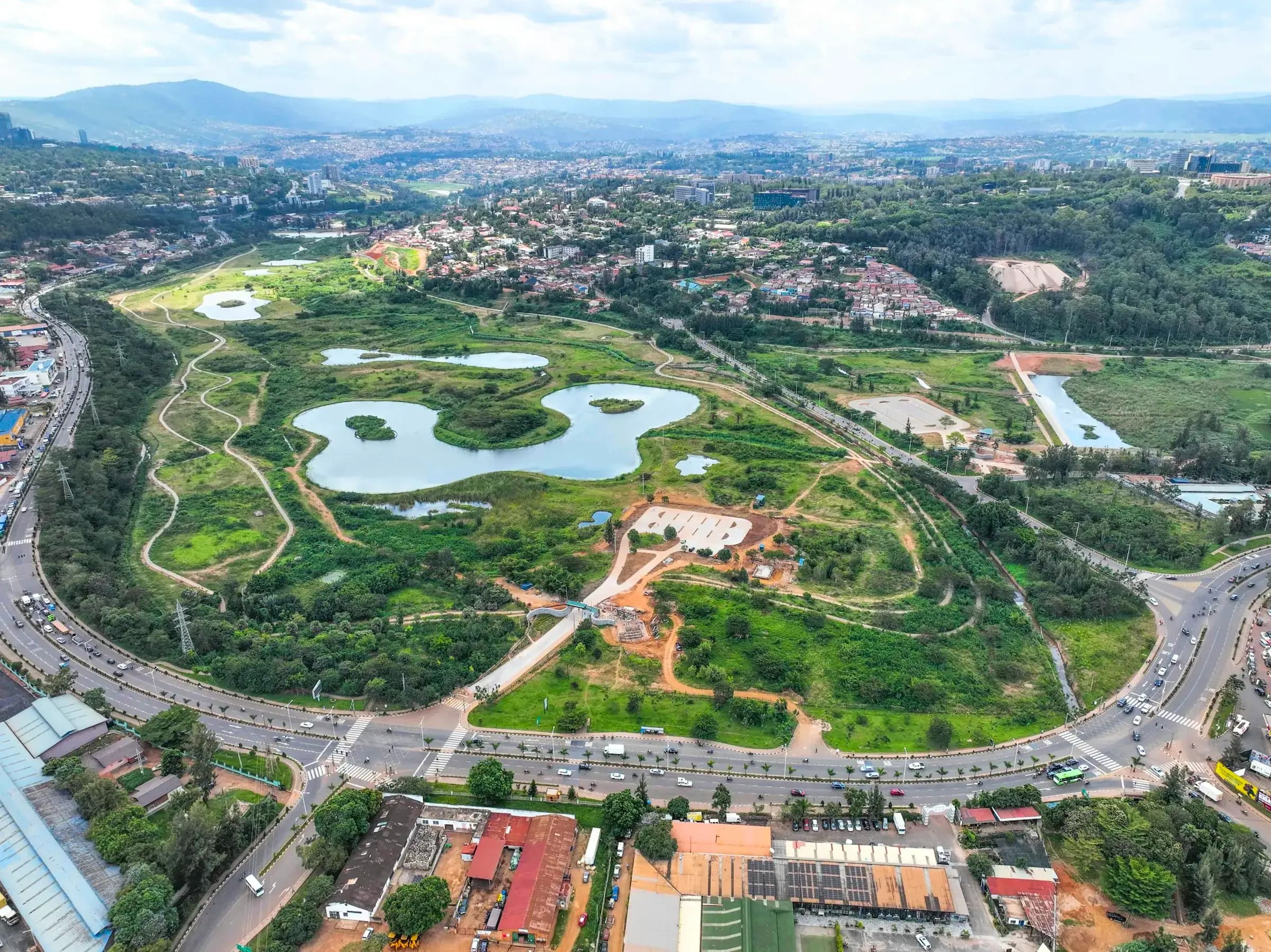 Aerial view of a green park and wetlands in Kigali with the city on the hills behind